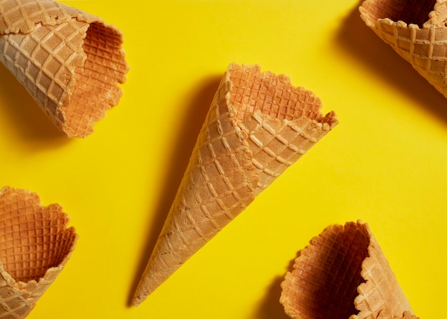 Süße Waffeleis-Eistüte auf gelbem Hintergrund, Sommer und leerem Konzept. Draufsicht. Flach liegen