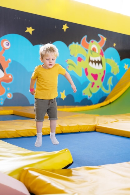 Süßer blonder kleiner Junge springt in eine Kinderaktivität im Trampolinpark
