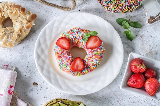 Süßer Donut mit bunten Streuseln und Erdbeeren