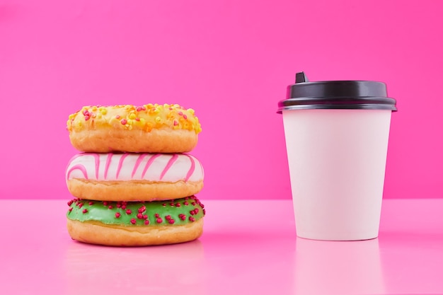 Süßer Donut oder Donut mit heißer Tasse frisch gebrühtem Kaffee oder Tee. Pappbecher zum Mitnehmen mit Donuts.