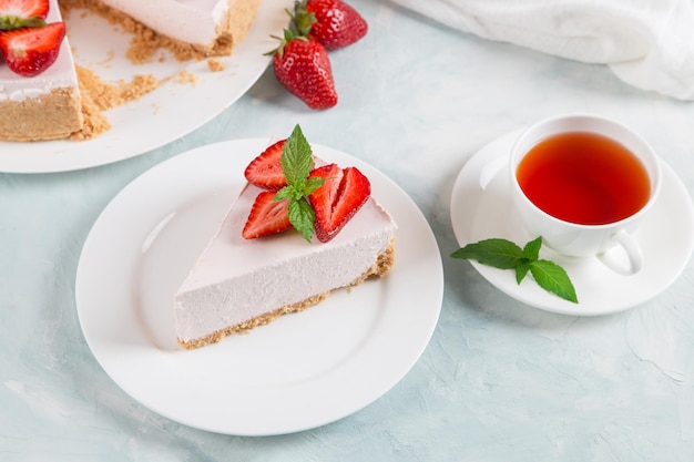 Süßer Frühstückstee und köstlicher Käsekuchen mit frischen Erdbeeren und hausgemachtem Minzrezept ohne Backen auf einem Tisch aus blauem Stein Kopieren Sie Platz