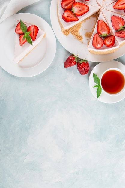 Süßer Frühstückstee und köstlicher Käsekuchen mit frischen Erdbeeren und hausgemachtem Minzrezept ohne Backen auf einem Tisch aus blauem Stein Kopieren Sie Platz