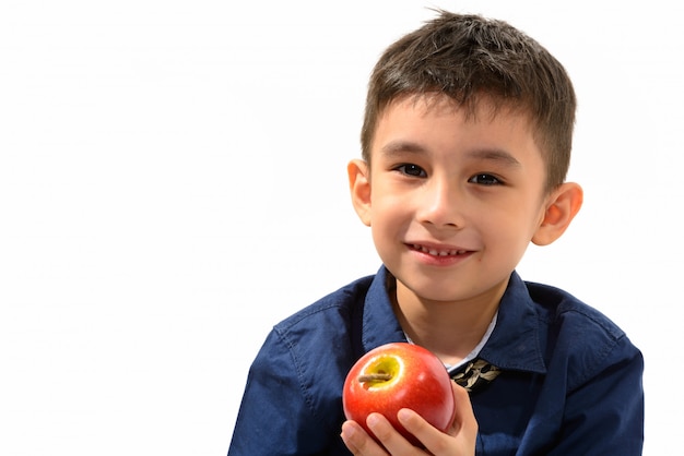 süßer glücklicher Junge, der lächelt und roten Apfel hält