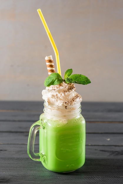 Foto süßer grüner fruchtsmoothie im glas auf holzhintergrund