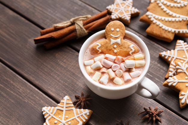 Süßer Ingwermann in einer Tasse heißer Schokolade mit Marshmallows auf Holztisch