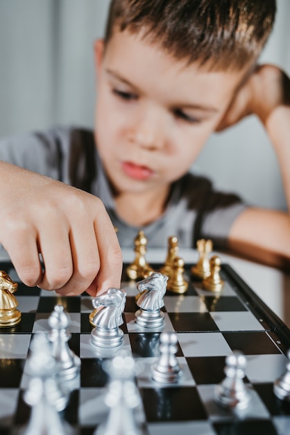 Süßer Junge 5 Jahre alt spielt Schach alleine in seinem Zimmer zu Hause