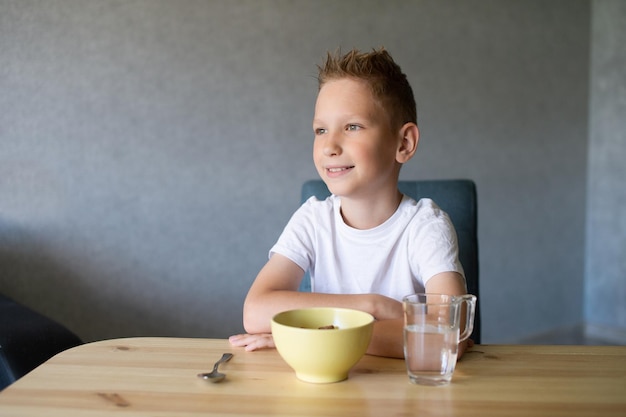 Süßer Junge isst zu Hause ein trockenes Frühstück und lächelt