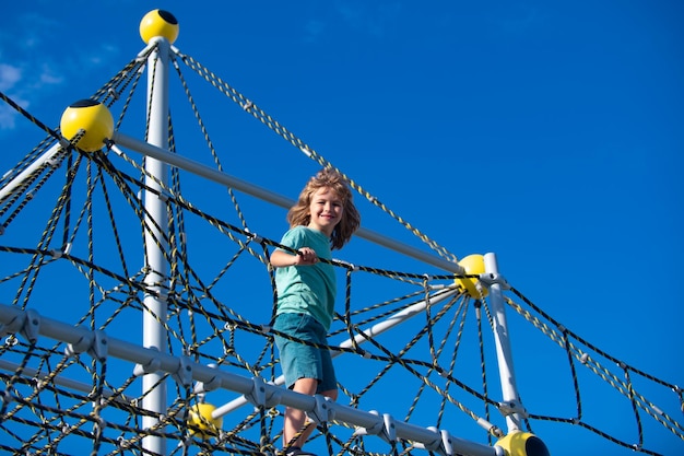 Süßer Junge Kletternetz im Park und Spaß auf dem Spielplatz