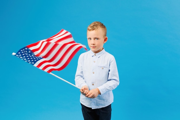 Süßer Junge mit amerikanischer Flagge im Innenstudio auf blauem Hintergrund