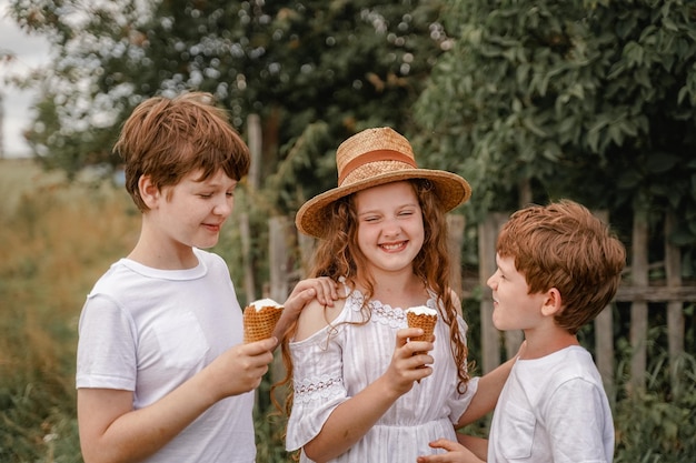 Süßer Junge mit Strohhut isst im Sommer Eis im Dorf