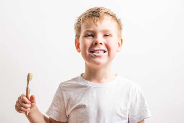 süßer Junge posiert mit Bambuszahnbürste im Mund, Kind putzt sich die Zähne