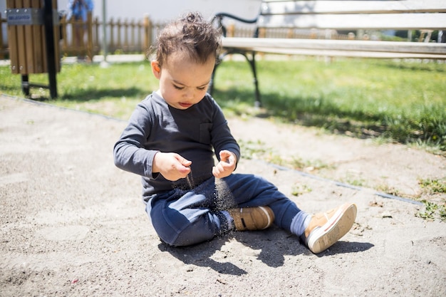 Foto süßer junge spielt mit sand auf dem spielplatz mit einem kleinkind