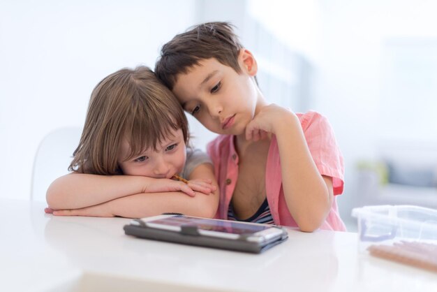 süßer kleiner bruder und schwester, die spaß zu hause haben kinder beim spielen auf tablet-computern