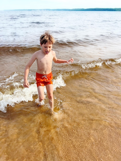 süßer kleiner Junge, der aus dem Ladogasee herauskommt. Sommer Strandurlaub Konzept.