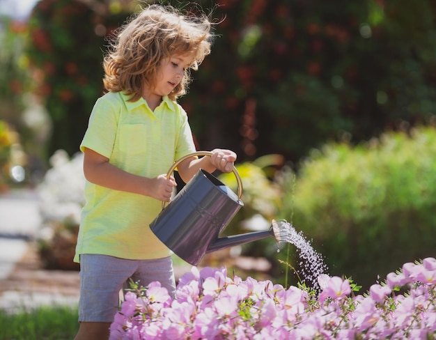 Süßer kleiner Junge, der Blumen mit Gießkanne gießt Kindergartenarbeit