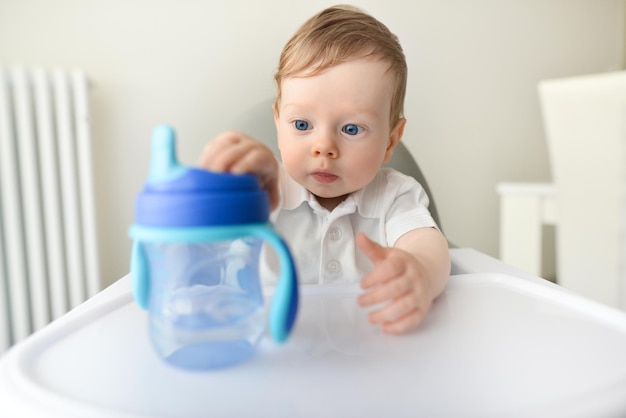 Foto süßer kleiner junge, der flasche mit wasser hält entzückender junge, der wegschaut und durstig ist