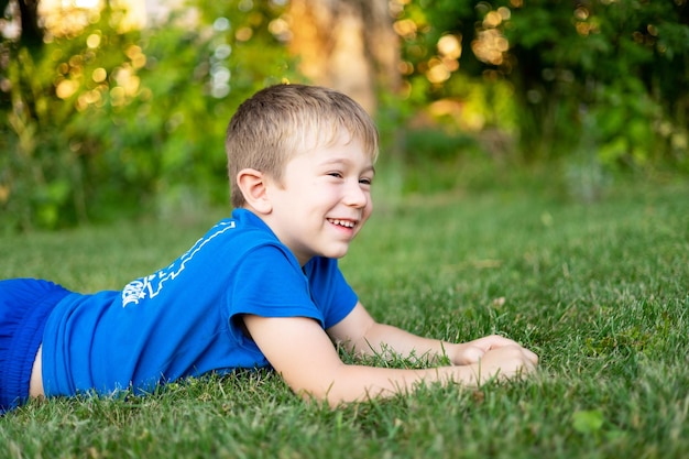 Süßer kleiner Junge, der im Sommer auf dem grünen Rasen im Park spielt. Kinderferien Erholung im Freien