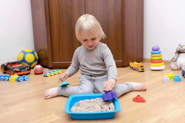 Süßer kleiner Junge, der zu Hause in einer sensorischen Box mit kinetischem Sand spielt Entwicklung feinmotorischer Fähigkeiten Frühe sensorische Bildung Aktivitäten Montessoriart-Kreativitätshandwerk im Tageskindergarten