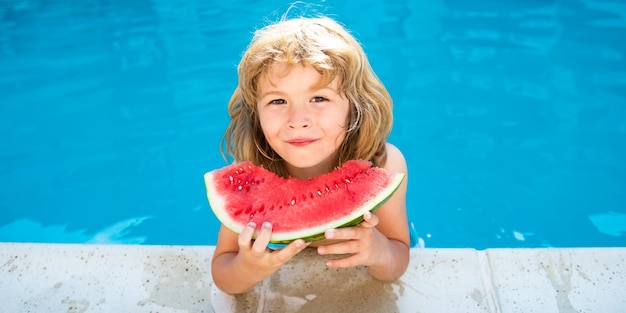 Süßer kleiner Junge im Schwimmbad, der Wassermelone isst, genießt es, Sommerkinder mit tropischen Früchten zu essen