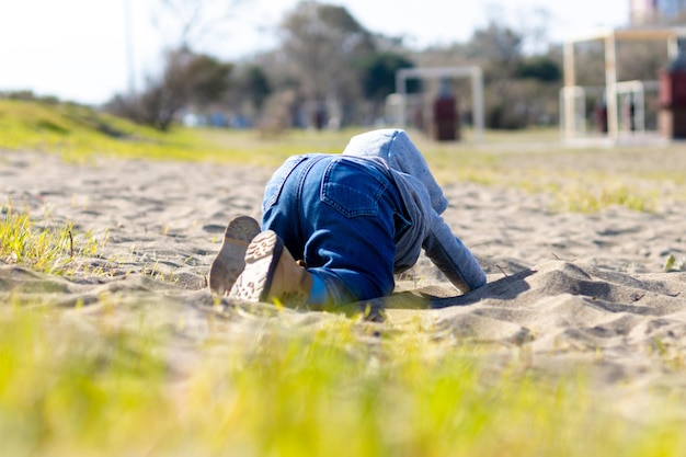 Süßer kleiner Junge in Hoodie und Jeans, der im Sand spielt Aktivität mit Kleinkind