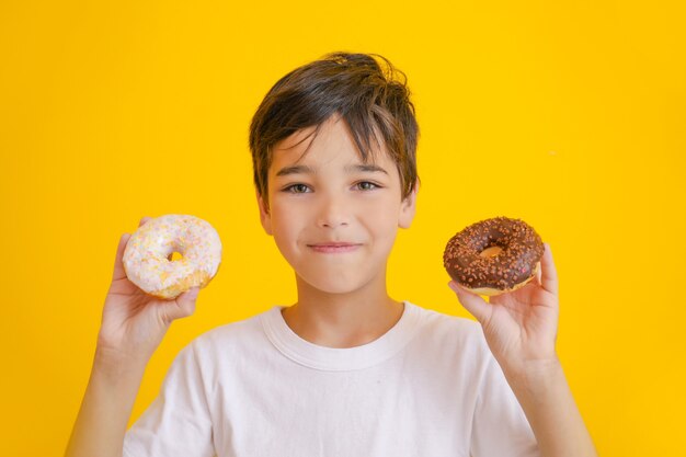 Süßer kleiner Junge mit leckeren Donuts auf Orange