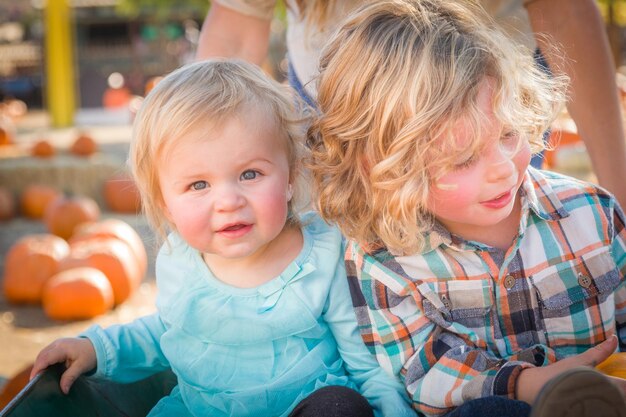 Süßer kleiner Junge spielt mit seiner kleinen Schwester in einer rustikalen Ranch-Umgebung am Pumpkin Patch