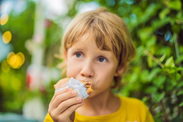 Süßer kleiner kaukasischer Junge, der Pfannkuchen isst und Orangensaft trinkt