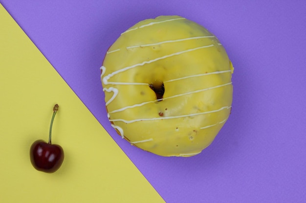 Süßer Krapfen, glasiert mit roten Kirschen auf einem farbigen Hintergrund Detailansicht von oben