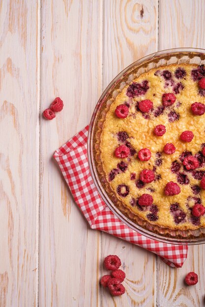 Süßer leckerer Kuchen mit gelierten und frischen Himbeerfrüchten in Auflaufform mit rotem Tischtuch