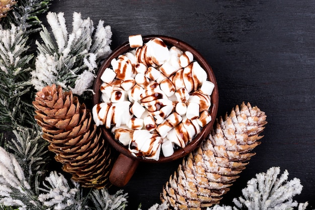 Süßer Marshmallow des Weihnachtsessens mit Schokolade in der braunen Tasse auf schwarzem Hintergrund