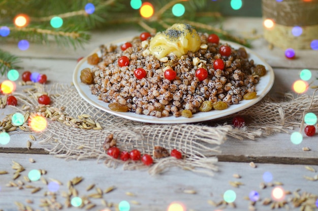 Süßer Pilaw mit Trockenfrüchten. Moderne Kutia mit kandierten Früchten. Teller mit Kutia mit Trockenfrüchten. Weihnachtsbrei mit Rosinen, kandierten Orangen und Mandeln.