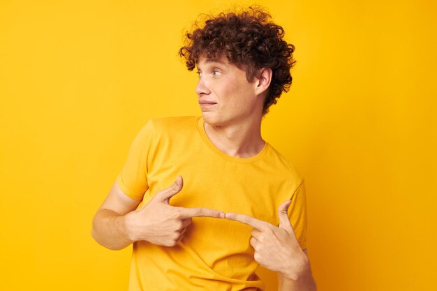 Süßer rothaariger Typ mit stylischem gelbem T-Shirt, der isolierten Hintergrund unverändert posiert