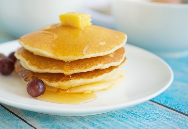 Süßer selbst gemachter Stapel Pfannkuchen mit Buttersirup und Frucht zum Frühstück.