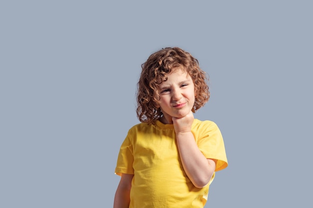 Süßes 5-jähriges kind im gelben t-shirt, das ihren kopf auf grau dreht