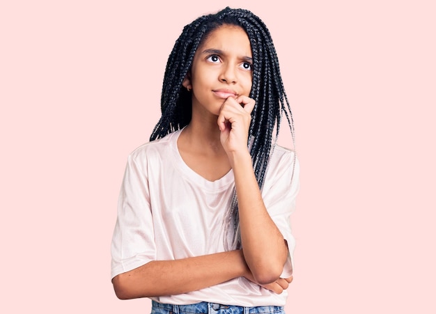 Süßes afroamerikanisches Mädchen in lässiger Kleidung, ernstes Gesicht, das über die Frage nachdenkt, mit der Hand am Kinn, nachdenklich über die verwirrende Idee