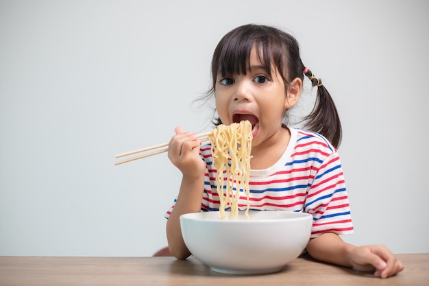 Süßes asiatisches Kindermädchen, das zu Hause köstliche Instant-Nudeln isst