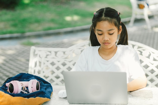 Süßes asiatisches Mädchen benutzt einen Laptop im Garten Lifestyle-Konzept