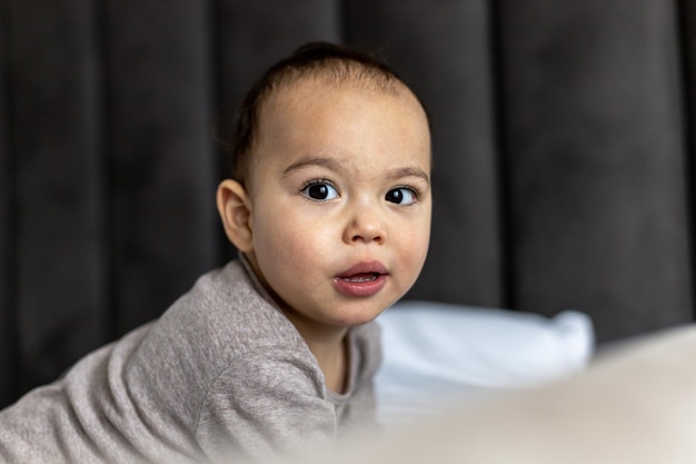 Süßes Baby auf dem Bett Gerade waches Kleinkind Lustiges Gesicht des molligen Kindes