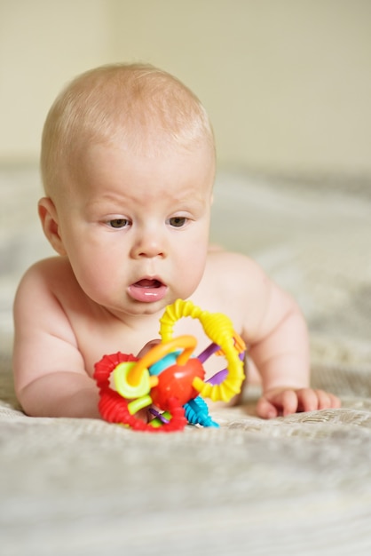 Süßes Baby, das Spielzeug auf dem Bett spielt