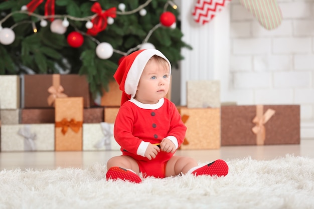 Süßes Baby im Weihnachtsmannkostüm zu Hause