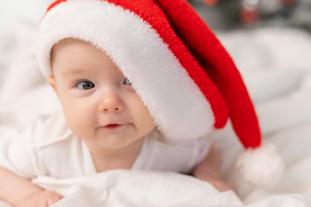 süßes baby in weihnachtsmütze zu hause im bett. Das erste neue Jahr. Weihnachtsgeschenk