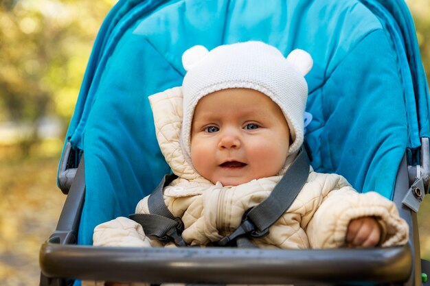 Süßes Baby sitzt in einem Kinderwagen im Herbstpark. Liebe und Zärtlichkeit. Nahaufnahme.