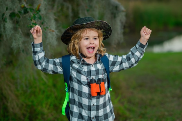 Süßes blondes Kind mit Fernglas mit Explorer-Hut und Rucksack in der Natur Child Explorer Wandern und Abenteuer