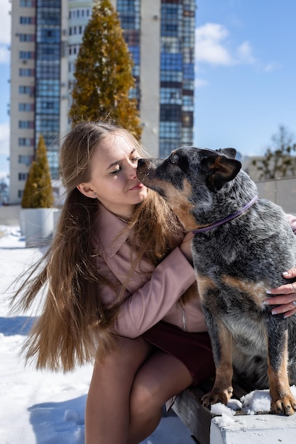 süßes blondes Mädchen umarmt einen Heiler-Hund in der Stadt