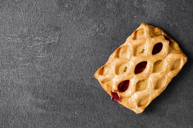 Süßes Brötchen mit Kirschmarmelade auf dunklem Hintergrund