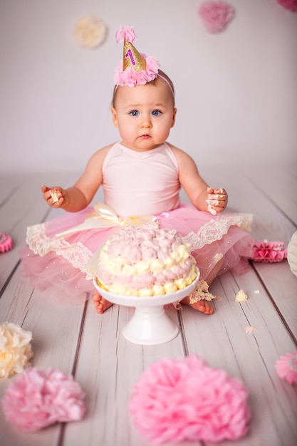 Süßes einjähriges kleines Mädchen mit ihrem ersten Geburtstagskuchen, das Zucker probiert und Geburtstag feiert