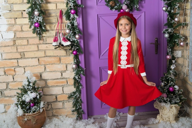 Süßes Festtagskleid. Kleines Modell mit modischem Look. Modisches kleines Kind. Kleine Fashionista auf Weihnachtsdekoration. Modemädchen bereit für Weihnachtsfeier. Kleines Mädchen im Weihnachtskleid.