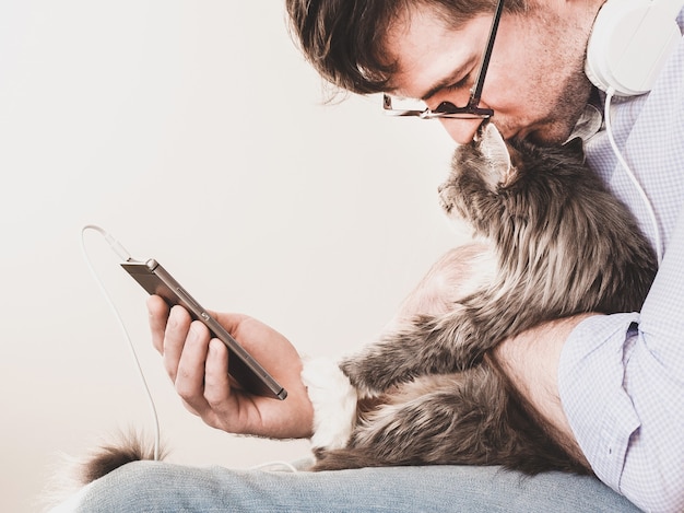 Süßes, flauschiges Kätzchen und ein Mann mit einem Telefon. Haustierpflegekonzept