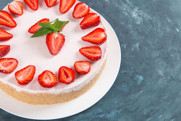 Süßes Frühstück köstlicher Käsekuchen mit frischen Erdbeeren und hausgemachtem Minzrezept ohne Backen auf einem dunkelblauen Steintisch Kopierraum