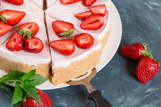 Süßes Frühstück köstlicher Käsekuchen mit frischen Erdbeeren und hausgemachtem Minzrezept ohne Backen auf einem dunkelblauen Steintisch Kopierraum